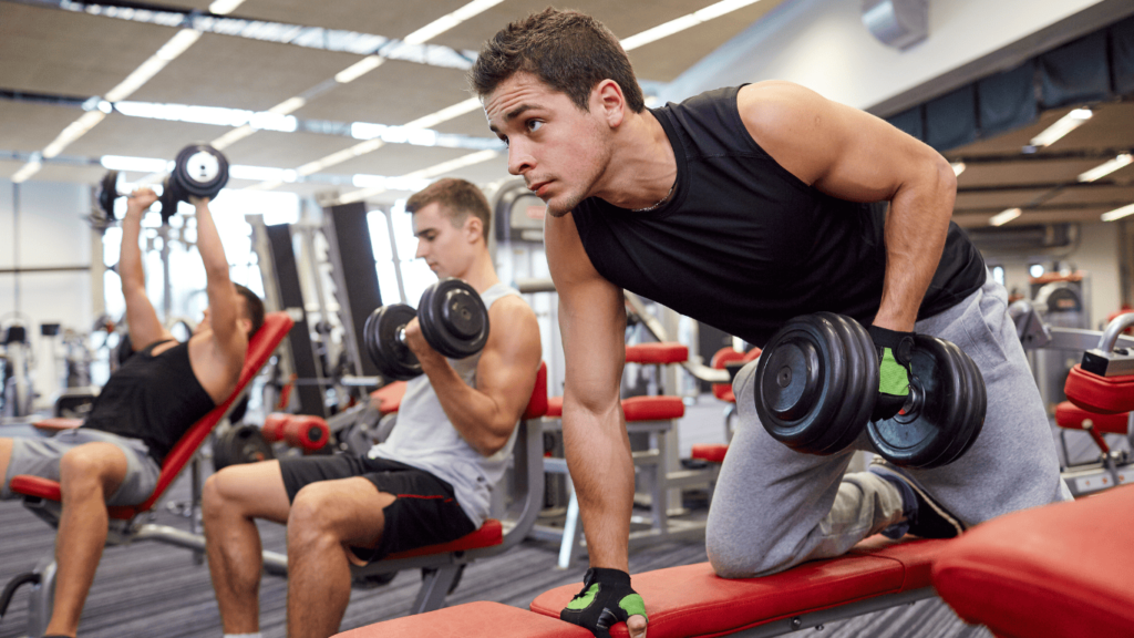 Tres chicos haciendo ejercicio con pesas en el gimnasio